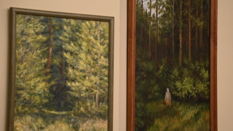 
                                        Dwa obrazy wiszą na ścianie pierwszy obraz przedstawia las na drugim pani w żółtej spódnicy szarej bluzce i chuście na głowie idzie do lasu                                        
