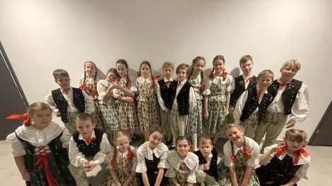 
                                        zdjęcie zespołu Mała Bandoska z przodu siedzą dziewczynki w długich sukniach z tyłu stoją chłopcy z dziewczynkami w kolorowych sukniach                                        